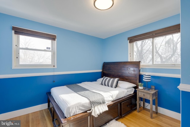 bedroom with multiple windows, wood finished floors, and baseboards