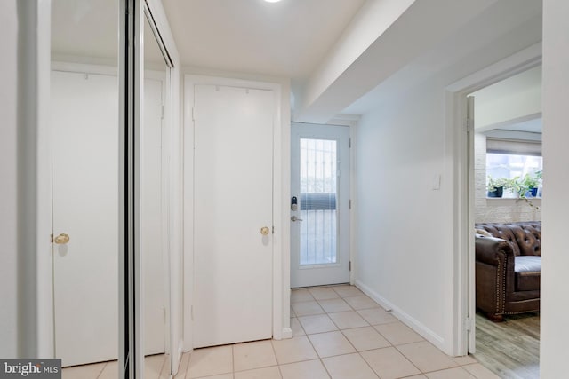 doorway to outside with light tile patterned floors, plenty of natural light, and baseboards