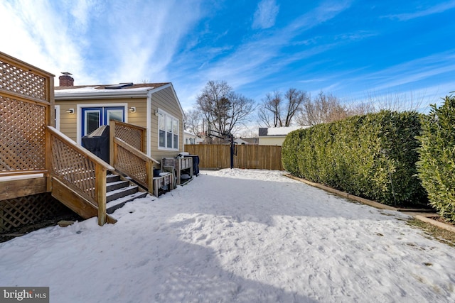 snow covered rear of property with fence, a chimney, and a wooden deck