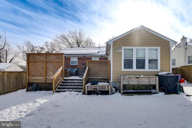 snow covered back of property with fence and a wooden deck