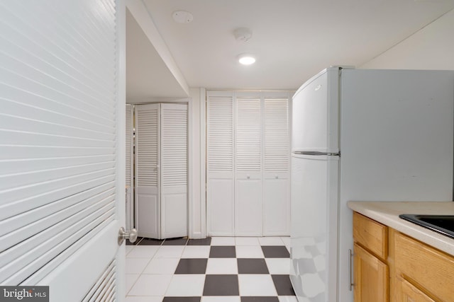 kitchen with freestanding refrigerator, light countertops, and light floors