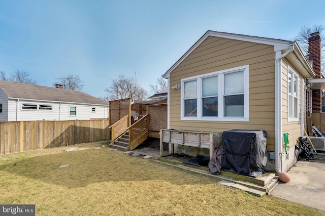 back of house with a yard, fence, and a chimney