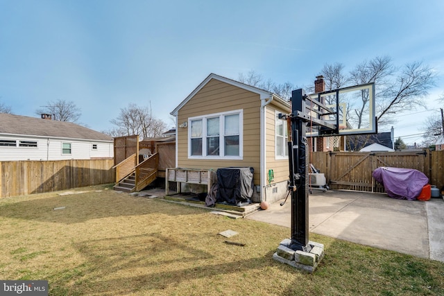 rear view of property featuring a gate, a fenced backyard, a lawn, and a patio