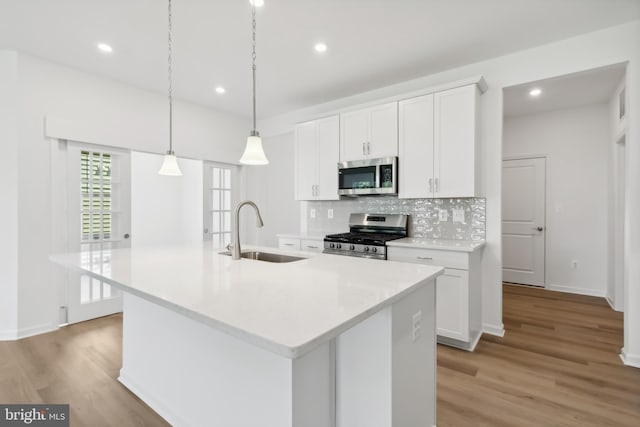 kitchen with sink, appliances with stainless steel finishes, an island with sink, and white cabinetry