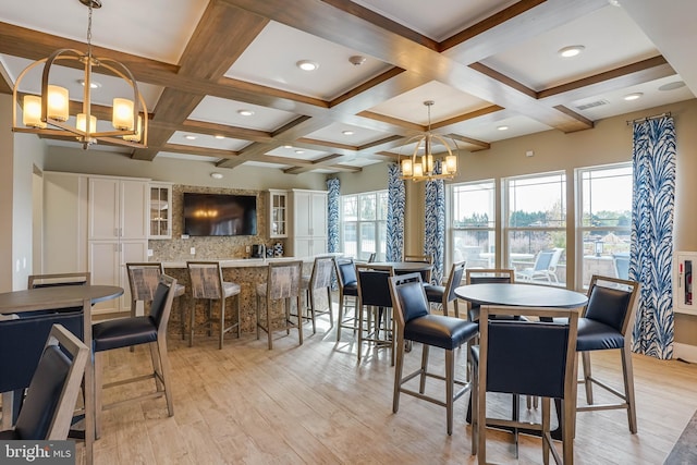 dining space with light wood-type flooring, beamed ceiling, a notable chandelier, and coffered ceiling