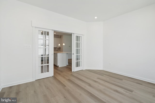 spare room with french doors, light hardwood / wood-style flooring, and sink