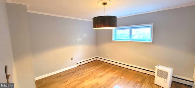 spare room with a baseboard heating unit, crown molding, and wood-type flooring