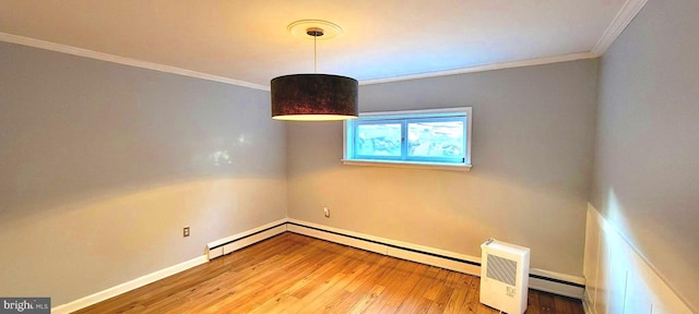 spare room with wood-type flooring, a baseboard heating unit, and crown molding