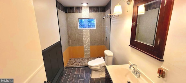 bathroom with toilet, vanity, and tiled shower