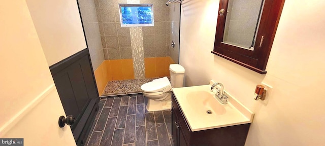 bathroom featuring toilet, vanity, and a tile shower