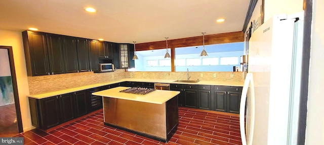 kitchen featuring decorative light fixtures, tasteful backsplash, a center island, sink, and appliances with stainless steel finishes