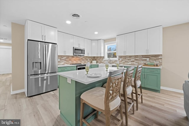 kitchen featuring white cabinets, a breakfast bar, stainless steel appliances, and a kitchen island