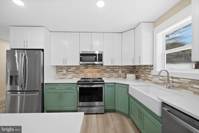 kitchen featuring appliances with stainless steel finishes, green cabinetry, and white cabinetry