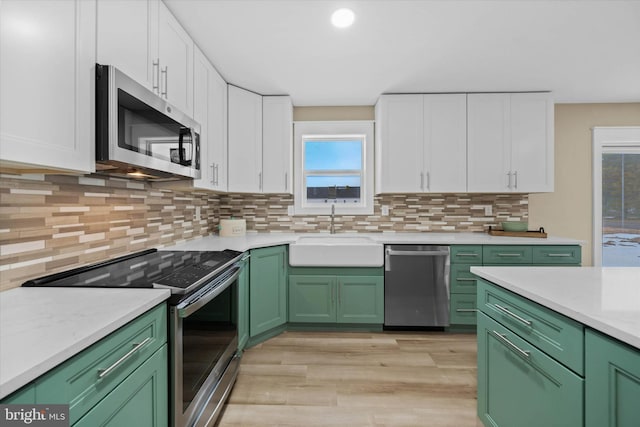 kitchen with decorative backsplash, sink, green cabinets, appliances with stainless steel finishes, and white cabinets