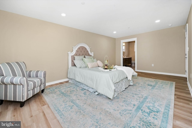 bedroom with ensuite bathroom and hardwood / wood-style flooring