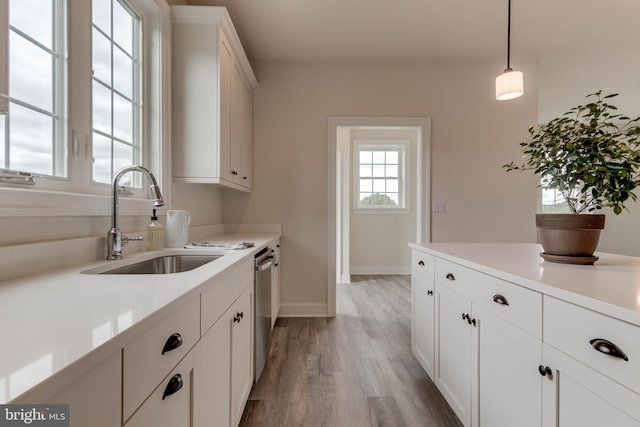 kitchen with dishwasher, pendant lighting, sink, white cabinetry, and light wood-type flooring