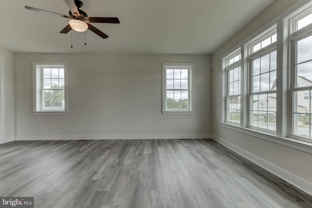 unfurnished room with ceiling fan, a healthy amount of sunlight, and light wood-type flooring