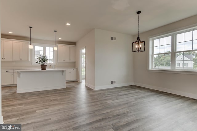 interior space featuring white cabinets, a center island, and pendant lighting