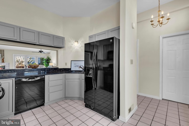 kitchen with light tile patterned floors, gray cabinets, ceiling fan with notable chandelier, black appliances, and decorative light fixtures