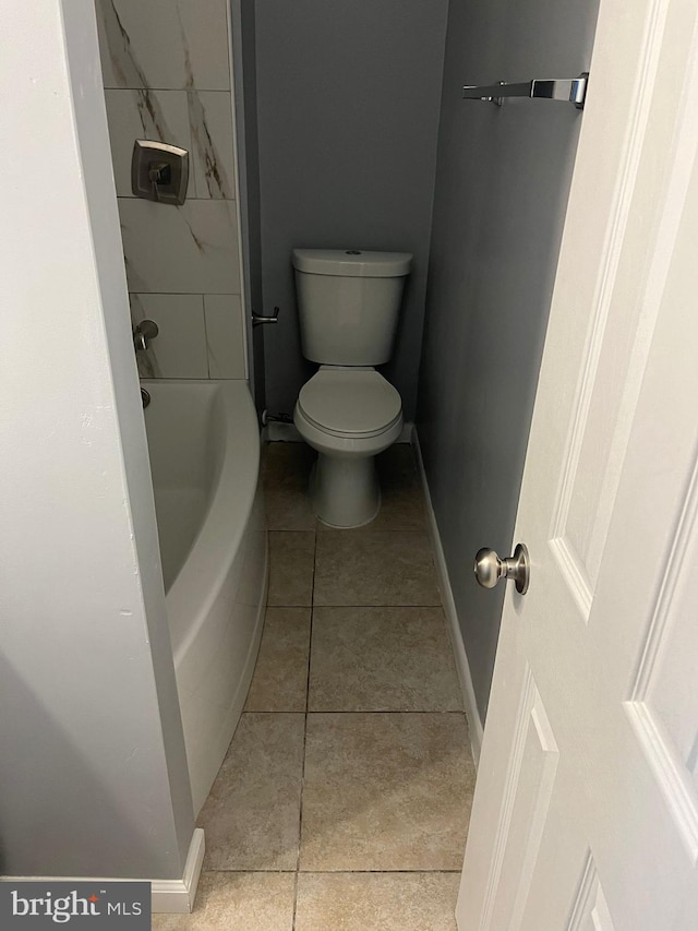 bathroom with tile patterned flooring, toilet, and a tub to relax in