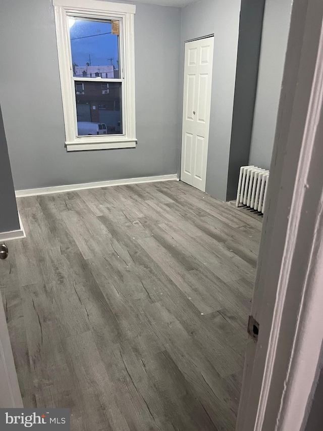 empty room with light hardwood / wood-style floors and radiator heating unit