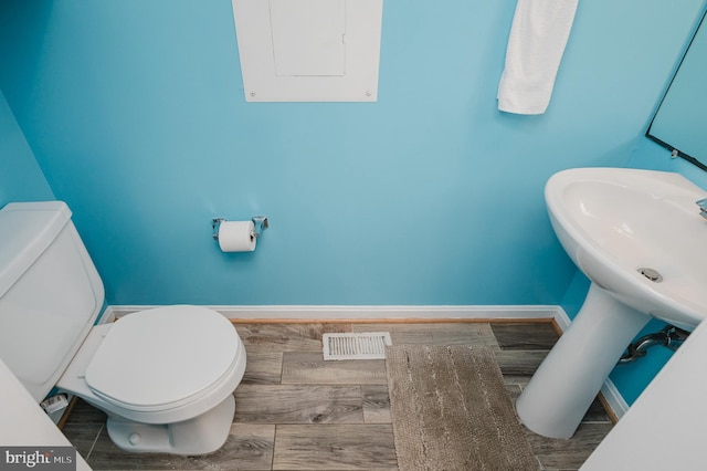 bathroom featuring hardwood / wood-style floors, electric panel, and toilet