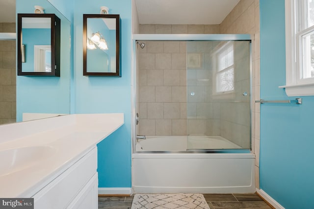 bathroom with vanity, hardwood / wood-style flooring, bath / shower combo with glass door, and a healthy amount of sunlight