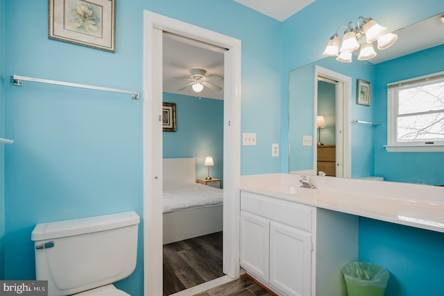 bathroom with vanity, ceiling fan with notable chandelier, hardwood / wood-style floors, and toilet