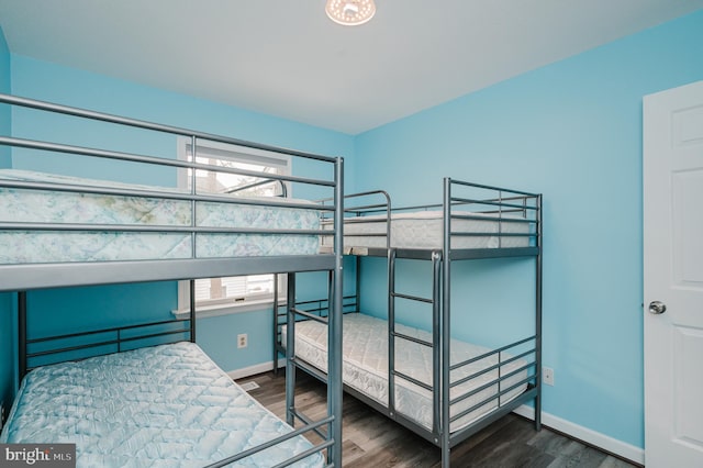 bedroom with multiple windows and dark hardwood / wood-style flooring