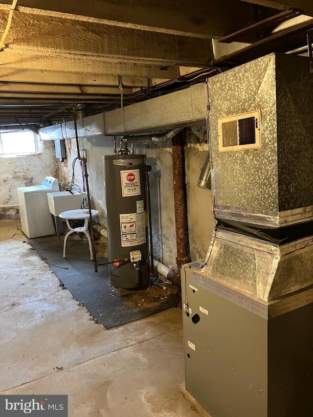 utility room featuring heating unit, water heater, sink, and washing machine and dryer