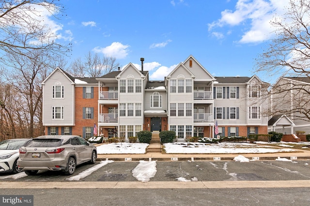 view of front facade with uncovered parking and brick siding