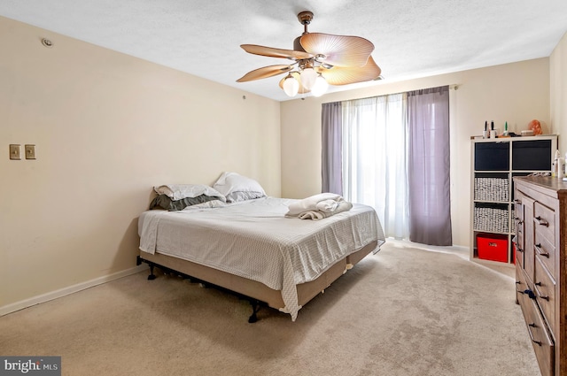 bedroom with light carpet, ceiling fan, a textured ceiling, and baseboards