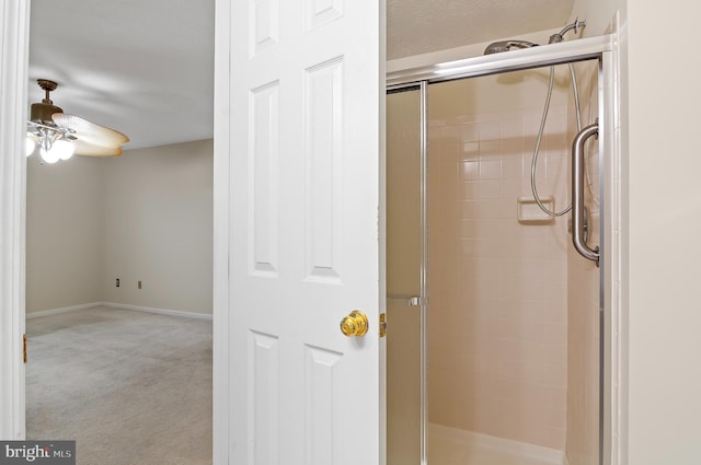 bathroom with a stall shower, a ceiling fan, and baseboards