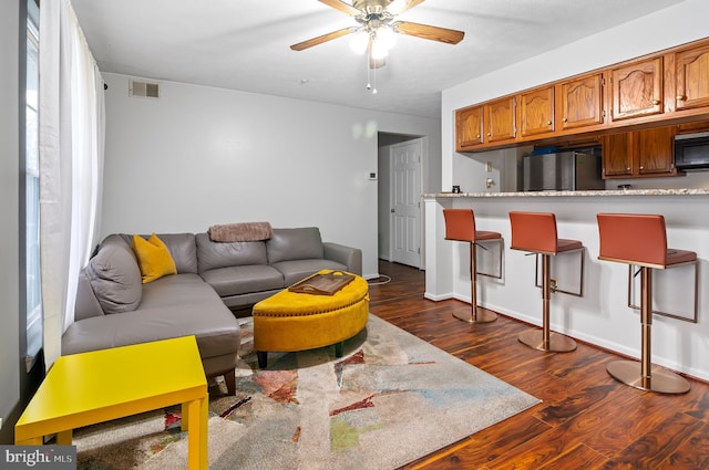 living area featuring ceiling fan, visible vents, and dark wood-type flooring