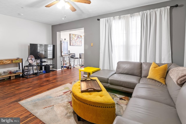 living area with a ceiling fan, baseboards, and wood finished floors