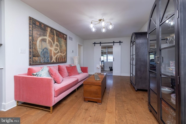 living room featuring light wood-type flooring, a barn door, baseboards, and visible vents