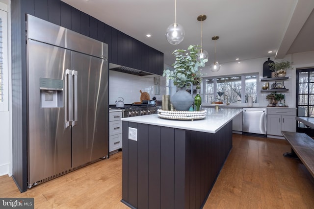 kitchen with appliances with stainless steel finishes, a kitchen island, light countertops, and light wood-style floors