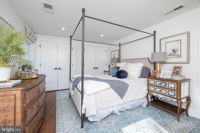 bedroom with recessed lighting, visible vents, multiple closets, and wood finished floors