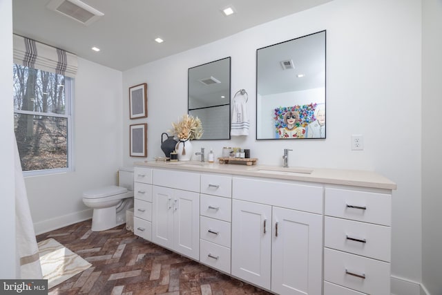 full bathroom with a sink, visible vents, toilet, and double vanity