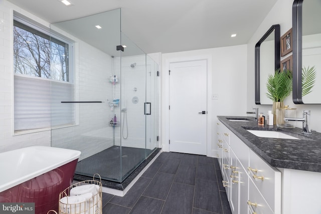 bathroom with double vanity, a stall shower, a freestanding bath, and a sink