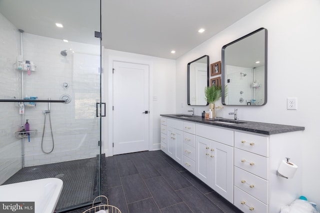 bathroom with double vanity, recessed lighting, a stall shower, and a sink