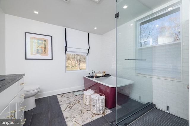 bathroom with a freestanding tub, toilet, tile patterned flooring, baseboards, and vanity