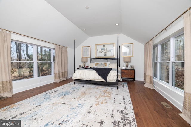 bedroom with lofted ceiling, multiple windows, wood finished floors, and visible vents