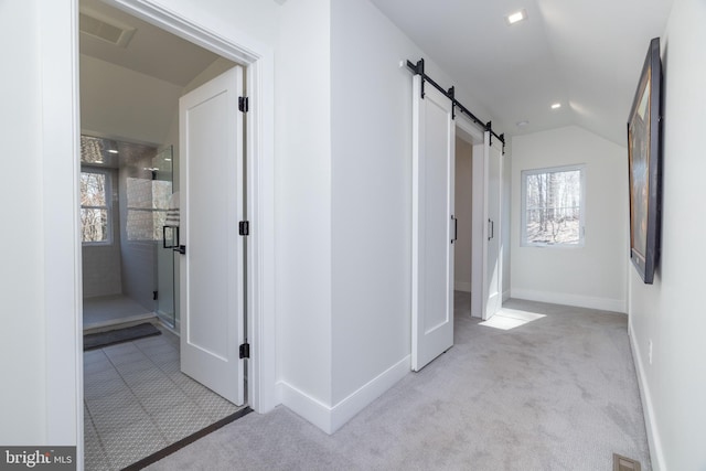 corridor featuring a barn door, plenty of natural light, light colored carpet, and visible vents