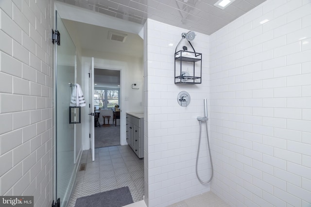 bathroom featuring tile patterned floors, visible vents, tile walls, tiled shower, and vanity