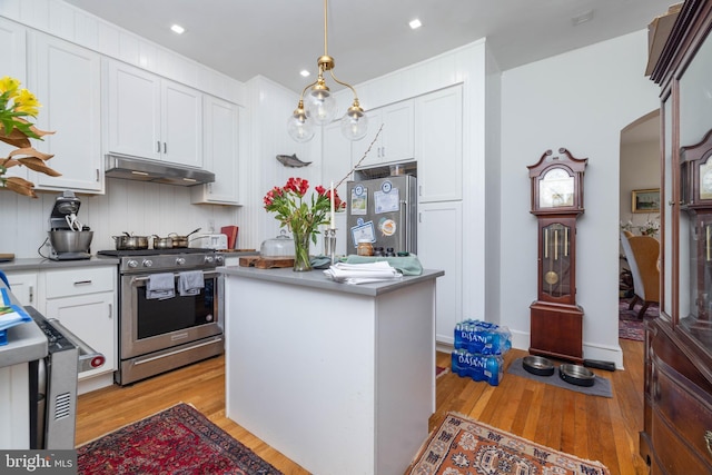 kitchen featuring a kitchen island, under cabinet range hood, light wood-style flooring, appliances with stainless steel finishes, and white cabinetry