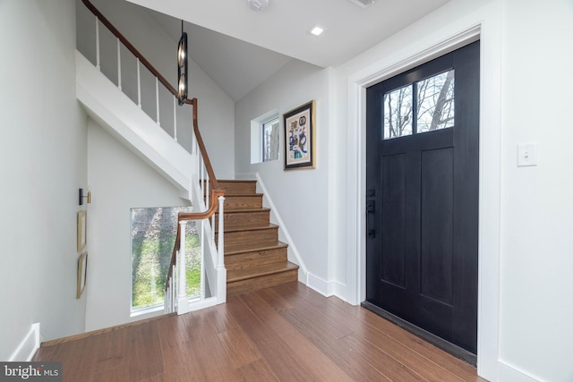 entryway with stairway, baseboards, wood finished floors, and vaulted ceiling