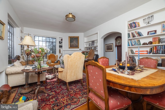 dining space with arched walkways and built in shelves