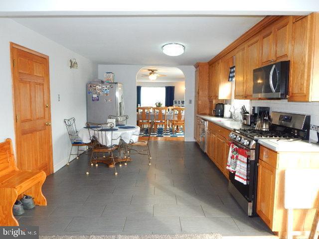 kitchen with ceiling fan, backsplash, appliances with stainless steel finishes, and dark tile patterned floors