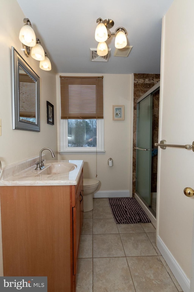 bathroom featuring vanity, toilet, a shower with door, and tile patterned flooring